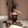 Woman wearing black lace bunny ear bodysuit with open-crotch design, sheer stockings, and posing on white rug indoors.