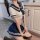 A woman wearing a sailor-style school uniform outfit, featuring a white crop top with navy accents and a matching pleated ski...