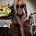 Woman in black lace cut-out bodycon mini skirt set with halter backless design, posing by halloween decor.