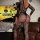 Woman wearing black lace cut-out bodycon mini skirt set with halter backless design, posing in halloween-themed room.