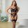 Woman modeling black embroidered lingerie set with floral details and fishnet stockings, enhancing small bust with chic europ...