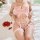 Sheer pink floral lace cami bra set with garter straps, styled on a model lying on a bed beside cherry tomatoes and flowers.