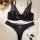 Black lace bra and panty set with red floral details, displayed on white fur with lipstick and pearls.