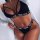 Woman wearing black sexy baby alphabet thong bikini set with strappy bra and open white shirt.
