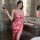 A woman elegantly poses in a luxurious bathroom, wearing a vibrant red floral dress with a deep v-neckline and a high slit. s...
