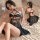 Woman modeling black sheer halter nightgown with lace-up front and back detail on bed. fan lei original sexy lingerie sleep d...
