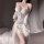 Woman wearing white feimu silk-look lounge dress with lace trim, sheer sleeves, and elegant drape — minimalist sensual sleepw...