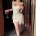 Woman in white feiniao moon gaze lace bodysuit holding wine glass, featuring mesh camisole and bodycon wrap dress for date ni...