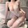 Woman wearing white lace feiniao moon gazer bodysuit with garter straps and bow details, kneeling on rug beside bathtub.
