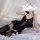 Woman wearing black lace feng qu cat lingerie set with sheer mesh bodysuit, open-crotch design, and suspender stockings on be...
