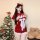 A woman poses beside a christmas tree wearing a festive red velvet lingerie set with white fur trim and a bow. she accessoriz...