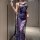 Woman wearing a blue lace slip dress with floral patterns, featuring a high slit and delicate straps, holding a feather acces...