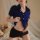 Woman wearing blue flirty airline hostess costume set with short skirt, posing seductively in bedroom setting.