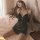 Woman wearing black floral moonlight sensual lace backless slip nightgown on bed with candles, elegant sheer sleepwear.