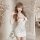 Woman wearing white cherry-print bodycon sleep dress with red trim, posing in elegant room with floral decor.