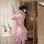 Woman wearing pink floral backless chemise with sheer fabric and side slit, styled as sensual sleepwear in soft-lit bedroom s...