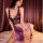 Woman modeling purple floral lace cheongsam set with deep v corset top, satin skirt, thong and garter belt on bed.
