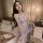 Woman modeling lavender flower moon seduction lingerie set with sheer lace, butterfly bows, and no-remove design in bedroom.