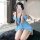 A woman wearing a blue fluffy pajama set with cat ears, taking a selfie indoors. the cozy dress features long sleeves and a r...