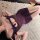 Woman lying on white rug wearing purple flybird moonlight sheer lace mesh bodycon mini dress with floral trim and bow details...