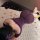 Woman wearing purple flybird moonlight lace mesh bodycon dress, lying on white rug with rose petals.