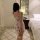 A woman stands in a bedroom wearing a french-inspired lace sleep dress with vintage floral patterns, holding a rose. the dres...