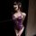 A woman poses in a purple french lace bodysuit with underwire, featuring intricate lace details and a sensual design.