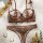 Brown french luxury lace lingerie set with floral embroidery, sheer cups, bow straps, and matching thong on white tulle.