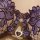Close-up of french lace lingerie set with purple floral embroidery and crystal buckle detail on sheer mesh bra.