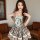 A charming model showcases the french retro square-neck puff sleeve dress, featuring sweet summer vibes with its plaid patter...