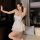 A woman poses elegantly in a white french-style summer sleepwear set, featuring a silky satin tie-back cami nightdress with r...