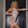Woman modeling white glow-in-the-dark mesh two-piece dress set with uv reactive lingerie design and no-remove feature.