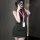 A woman poses with a smartphone, wearing a form-fitting maroon top and black skirt, paired with a lanyard badge. the outfit f...