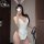 A woman poses in a white bunny-themed cosplay outfit, featuring a cute bodice with buttons and ruffles, along with bunny ears...