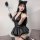 A woman poses wearing a black leather mini skirt set with cat ears and accessories, styled for japanese anime cosplay.