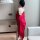 A woman stands facing away from the camera, wearing a vibrant red sheer corset set. the fabric drapes elegantly over her shou...