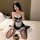 A woman sits on a bed wearing a black and white hanno jk uniform lingerie set, featuring delicate lace details. she holds a c...