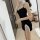 A woman poses in front of a mirror wearing a black hanno sensual lingerie set, featuring lace details and a playful design, p...