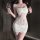 A woman wears a white lace bodysuit with open-crotch design, holding a glass of wine. the outfit features intricate lace deta...