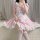 A person wearing a japanese anime maid costume, featuring a pink and white dress with ruffles and bows, perfect for restauran...