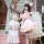 A person dressed as a maid in a cute pink uniform holds a matching plush rabbit doll, both featuring soft details and playful...