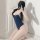 A woman poses in a navy blue one-piece swimsuit with white trim, capturing her reflection on a mirror. the design features a ...
