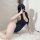 A woman poses on a fluffy rug wearing a navy blue one-piece swimsuit, capturing her reflection in a mirror. the design featur...