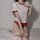 A woman models a japanese gymnastics outfit, featuring a white crop top with red trim, matching red shorts, and knee-high soc...
