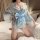 A woman poses on a bed wearing a light blue japanese kimono-style lingerie set. the outfit features a delicate floral pattern...