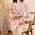 A woman sits on a chair holding a cup, wearing a pink floral japanese kimono-style robe. the outfit features a deep v-necklin...
