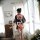 A woman stands by a window wearing a japanese kimono-style lingerie set, featuring vibrant floral patterns and a bow tie, per...