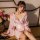 A woman wears a delicate pink japanese kimono-style sleepwear set, featuring floral patterns and a deep v-neckline, perfect f...