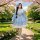A charming girl walks through a blossoming garden wearing a cute new japanese lolita dress. the dress features a soft blue co...