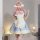A woman models a japanese-style maid outfit, featuring a blue and white dress with ruffles, a large pink bow, and lace detail...